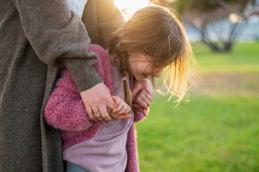 A comforting scene of a parent holding a small child in their arms in a park, representing care and parental support in custody cases managed by Judith Ramos, Attorney at Law in Fort Lauderdale, Florida.