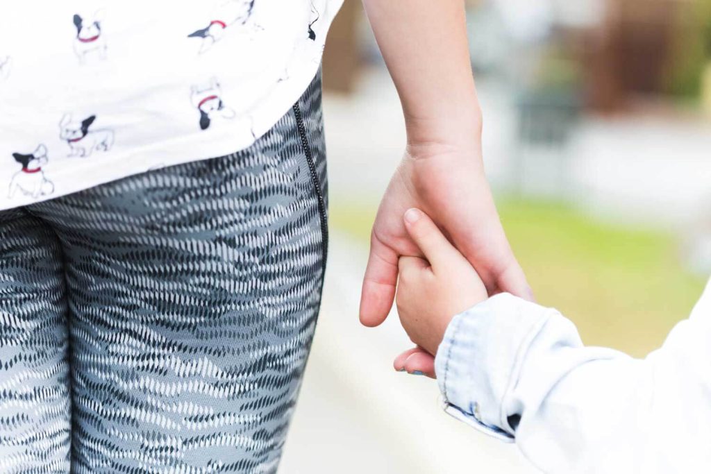 Close-up view of a young child holding an adult’s hand, representing security and parental support in child support cases managed by Judith Ramos, Attorney at Law in Fort Lauderdale, Florida.