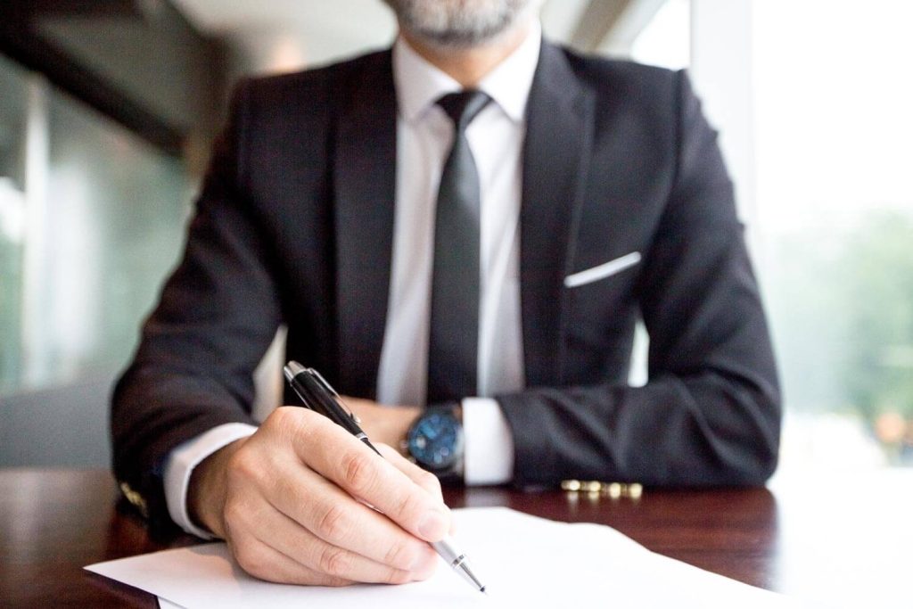 A professional discreetly signing legal documents, face not visible, representing Judith Ramos, Attorney at Law’s commitment to confidentiality in managing complex divorce cases in Fort Lauderdale, Florida.