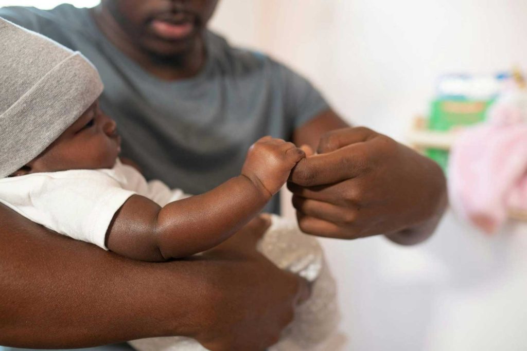 A father gently holding his baby’s hand, representing care and paternal love in father’s rights and paternity cases managed by Judith Ramos, Attorney at Law in Fort Lauderdale, Florida.